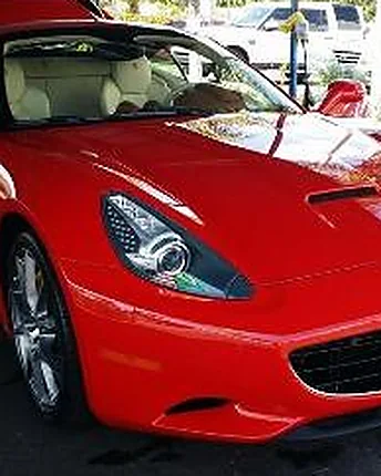 A red Ferrari with a hand polished hood and clean wheels parked on the wash lot.