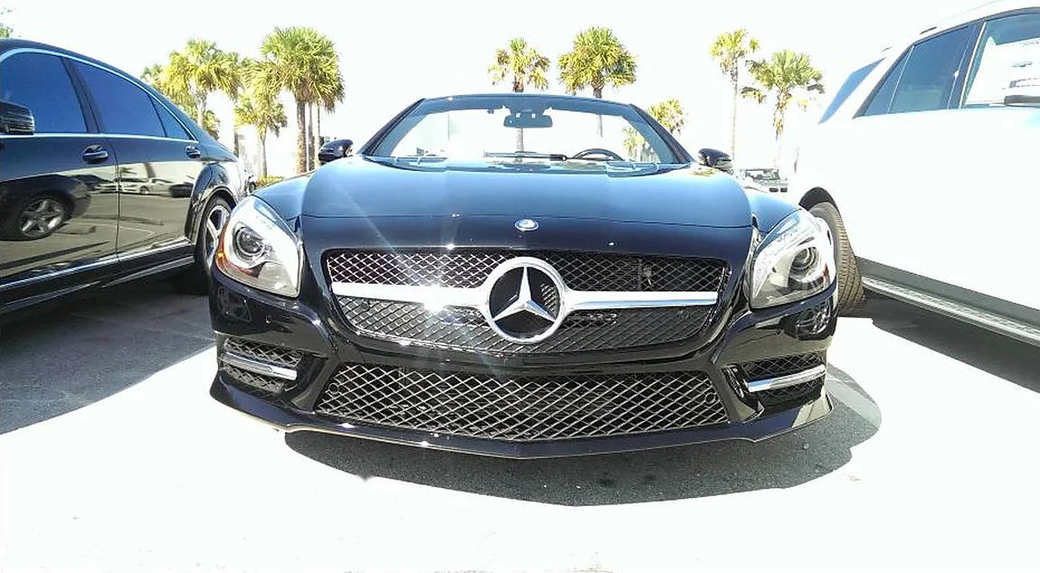 A black Mercedes SL roadster washed by hand at The Car Salon, its paint and chrome grille gleaming under the Fort Lauderdale palms.